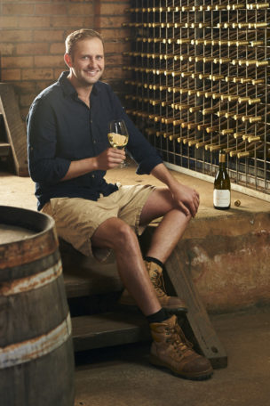 Hugh Mugford holding a glass of wine in Moss Wood cellar