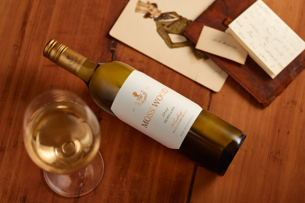 3_20240704_MOSSWOOD Semillon 2023_Creatives An atmospheric image of a Moss Wood Semillon 2024 wine bottle laying on a table.